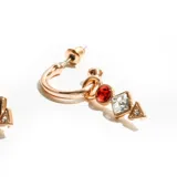 Aros tipo argolla dorados con dijes colgantes de cristal en forma de círculo rojo, cuadrado transparente y triángulo dorado.