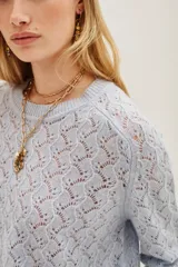 Sweater de punto calado con diseño de ondas, cuello redondo y mangas largas con puños acanalados.