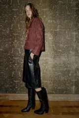 Bermuda negra de tiro alto con efecto piel, bolsillos delanteros y falsos bolsillos de vivo en la espalda. Cierre frontal con cremallera, botón interior y gancho.