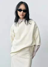 Jersey de punto fino color crema, con diseño oversize, cuello redondo y mangas cortas.