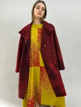 Tapado de lana merino afieltrada con diseño artesanal teñido en tonos violeta y fucsia. Presenta cuello elevado, cierre frontal con broches ocultos, bolsillos laterales y un corte ligeramente más largo en la parte trasera.