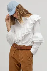 Camisa blanca de algodón con cuello clásico, cierre frontal de botones y volados dobles que recorren el frente, la espalda y las mangas.