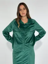 Chaqueta verde esmeralda de terciopelo con cuello camisero, cierre frontal con botones, dos bolsillos de parche con solapa en el pecho y manga larga.