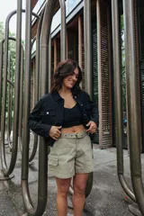 Campera negra de estilo utilitario, con cuello camisero, cierre frontal y botones metálicos. Presenta bolsillos con solapa en el pecho y un calce ligeramente holgado.