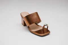 Sandalias de cuero color bronce con taco cuadrado y tira ancha sobre el empeine. Presentan un aro metálico plateado que separa el dedo gordo del resto.