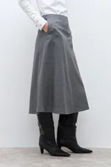Falda midi de corte acampanado con estampado de cuadros pequeños en tonos grises. Presenta un diseño de tiro alto y estructura firme.