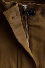 Campera corta verde militar en mezcla de lino, con cuello elevado, mangas raglán, bolsillos frontales con solapa y botones, y cordón ajustable en el bajo.