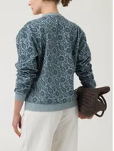 Buzo de algodón orgánico con cuello redondo y mangas largas. Presenta un diseño estampado con motivos florales y paisley en técnica flock sobre fondo gris.