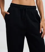Pantalón de corte recto confeccionado en algodón con felpa, de color marrón. Presenta cintura elástica con cordón ajustable y diseño holgado.