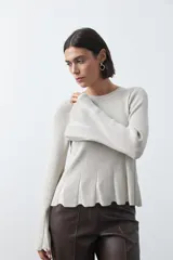 Top de tejido acanalado con sutil acabado metalizado, de silueta entallada con diseño peplum en la cintura y mangas largas levemente acampanadas.