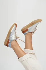Zapatillas plateadas con detalles en marrón y celeste, cordones finos color beige y suela de goma color caramelo.