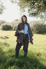 Camisa de jean azul claro con cuello alto, cierre frontal de botones y mangas largas con detalles de volados horizontales y puños con volados.