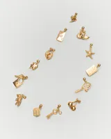 Aro colgante dorado con forma de dado y detalles de circonitas blancas.