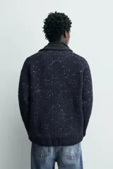 Jersey de punto con textura chenilla, de corte regular, cuello redondo y manga larga. Presenta un diseño de tejido con motas de contraste en color azul marino.