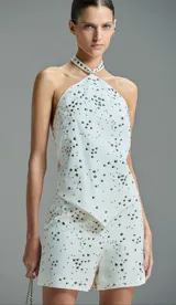 Short blanco con apliques de tachas metálicas distribuidas en patrón de explosión.