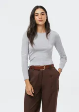 Blusa de punto gris claro melange, de tejido liviano, corte ajustado al cuerpo, cuello redondo y manga larga.