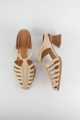 Sandalias de cuero color beige estilo cangrejera con punta fina, diseño de tiras entrelazadas, tira ajustable en el tobillo con hebilla dorada y taco geométrico de madera.