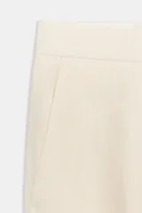 Pantalón color crema de tiro alto con bolsillos delanteros y falsos bolsillos traseros. Tiene una pequeña abertura lateral en el ruedo y cierre frontal con cremallera y gancho metálico.