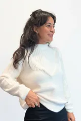 Sweater de punto color blanco, con cuello alto y detalle de escote en V con terminaciones desflecadas. De manga larga con puños acanalados y diseño holgado.