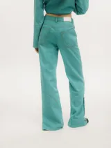 Pantalón de jean de corte recto y tiro medio, con efecto gastado. Presenta una hilera de botones en los laterales de los botapiés y bolsillos delanteros y traseros.