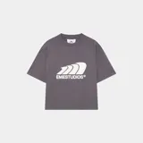 Camiseta de manga corta, corte 'boxy fit', color gris oscuro, con un gran estampado frontal en blanco que simula olas o viento y el texto 'EMESTUDIOS®' debajo.
