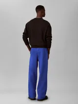 Pantalón de felpa azul con cintura elástica, pierna recta y costuras delanteras decorativas. Cuenta con un pequeño bordado en el muslo.