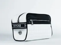 Necessaire Tiffosi bicolor blanco y negro, con diseño acolchado en cuadrillé en la parte inferior y liso en la superior. Cuenta con cierre principal, bolsillo frontal con cierre y una banda lateral con el logo de la marca.