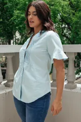 Camisa celeste con cuello mao, mangas cortas con volados y cierre frontal con botones.