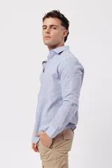 Camisa de manga larga para hombre, color azul claro jaspeado, con cuello clásico y botones blancos. Corte ajustado (slim fit).