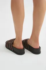 Sandalia plana con plataforma negra y tira ancha de pelo con estampado animal print tipo leopardo, decorada con tachas metálicas en los bordes.
