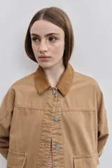 Campera de gabardina tostada, con cuello camisero de pana marrón, cierre frontal de botones metálicos y bolsillos delanteros aplicados con solapa.