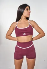 Conjunto deportivo compuesto por un top y un short de tiro alto en color bordó con detalles de ribetes blancos. El top presenta breteles finos y el logo 'bk.' estampado en el frente. El short es ajustado y cuenta con una banda elástica en la cintura.