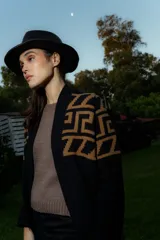 Saco tejido de punto con diseño de guarda inca en la parte superior. Presenta bolsillos frontales con detalles de tiras de cuero y flecos. De corte recto y largo medio, con terminaciones en tejido acanalado.