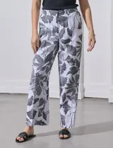 Pantalón de lino blanco con estampado de hojas en negro, de corte recto y pretina ancha con pasadores.