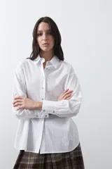 Camisa de corte relajado y diseño clásico, confeccionada en tela de algodón color celeste. Presenta cuello tradicional, cierre frontal con botones y mangas largas con puños rectos.