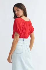 Blusa roja con escote cuadrado, mangas cortas abullonadas y cierre frontal con botones.