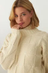 Buzo de tejido de punto industrial color crema, con cuello medio y diseño de parches cuadrados con diferentes texturas de punto.