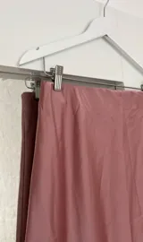 Pollera midi de seda color rosa, con cintura elástica.