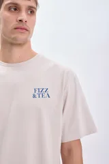 Camiseta manga corta oversize color gris claro con estampa azul en la espalda que incluye texto "Fizz & Tea" y el dibujo de un vaso con hielo.
