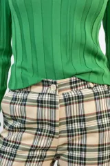 Pantalón de corte recto con estampado de cuadros escoceses en tonos beige, negro y verde. Presenta bolsillos delanteros funcionales y cierre frontal con botón.