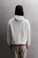 Sudadera regular fit de tejido polar con textura efecto pelo, color gris claro. Cuenta con cuello subido, capucha ajustada, manga larga ranglán, bolsillos laterales en la cadera y bajo asimétrico más largo en la espalda. Los acabados son con cinta elástica.