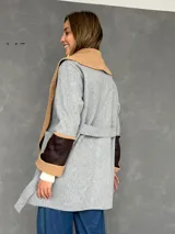 Saco de paño gris con solapas amplias de corderito color tostado. Presenta detalles de parches en cuero sintético marrón en las mangas y puños con vuelta de corderito.