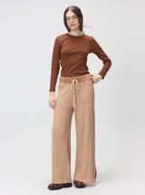 Pantalón de tejido jacquard con textura geométrica en tonos tostado y beige, de tiro medio, cintura elástica con cordón de ajuste y pierna ancha.