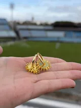 Par de dijes colgantes con forma de sol, realizados en acrílico color azul vibrante, diseñados para ser utilizados en aros tipo argolla.