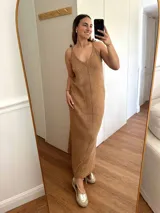 Vestido largo tejido en hilo de algodón y lurex color beige claro, con escote en V, tiras regulables en los hombros y tajos laterales. Presenta un patrón de puntos calados en forma de zigzag.