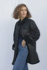 Campera tipo gamulán de cuero genuino en color marrón, con interior y detalles en corderito sintético color crema. Presenta cierre frontal con botones, cuello solapa y puños con vuelta.