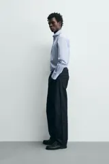Camisa de corte regular fit confeccionada en tejido de algodón con diseño de rayas verticales finas. Presenta cuello abotonado, manga larga con puños abotonados, bolsillo plastrón en el pecho y cierre frontal con botones.