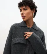 Campera de punto con textura, corte recto y cuello clásico. Presenta cierre frontal con botones y dos bolsillos aplicados con solapa en el pecho.