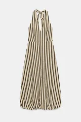 Vestido midi de corte globo con estampado de rayas verticales, cuello halter anudado, escote en pico y espalda descubierta. Presenta bajo abullonado con elástico interior y cierre lateral con cremallera oculta.