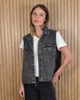 Chaleco de denim 100% algodón en color negro gastado, con cuello camisero, cierre frontal de botones metálicos y bolsillos delanteros con solapa.